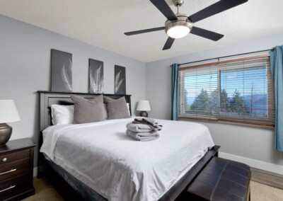 Primary bedroom with king bed and lake-facing window at MacKenzie House, Peachland BC