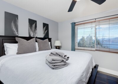 King bed with fresh linens and towels in the primary bedroom, MacKenzie House Peachland